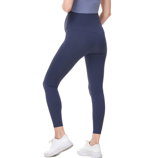 Pregnant Person wearing navy leggings and white sneakers on a white background