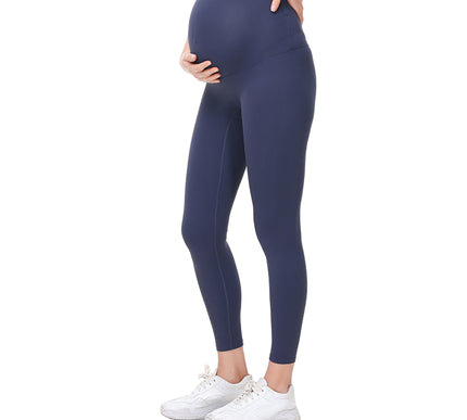 Pregnant Person wearing navy leggings and white sneakers on a white background