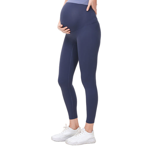 Pregnant Person wearing navy leggings and white sneakers on a white background