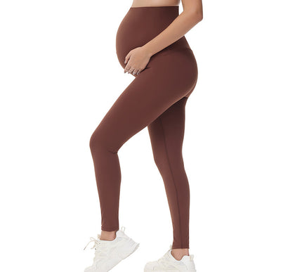 Brown leggings worn by a Pregnant person on a white background