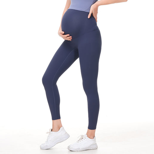 Pregnant Person wearing navy blue leggings and white sneakers on a white background