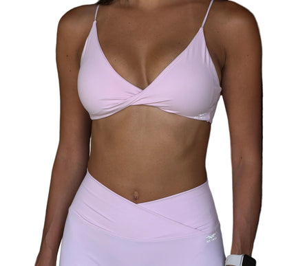 Person wearing a light pink sports bra and leggings set with a blurred background