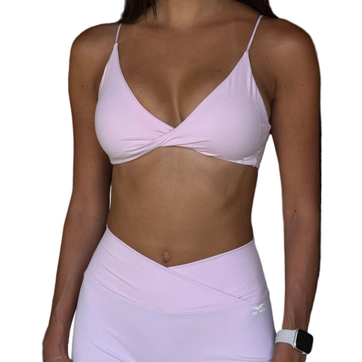 Person wearing a light pink sports bra and leggings set with a blurred background