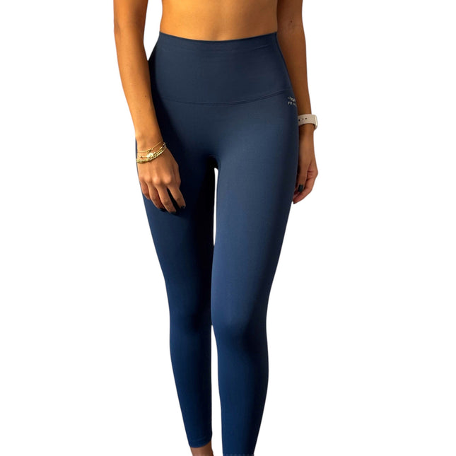 A pair of dark blue high-waisted activewear leggings on a female model. The model is wearing a yellow top and the leggings are form-fitting with a high waist design.